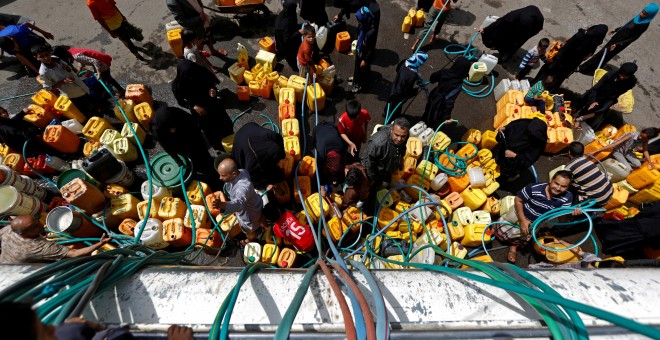 Ciudadanos yemeníes llenan sus bidones de un camión cisterna de las organizaciones humanitarias.  REUTERS/Khaled Abdullah