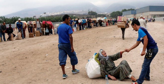 Un hombre ayudando a una de las mujeres al caerse mientras transportaba los materiales / REUTERS -  Youssef Boudlal