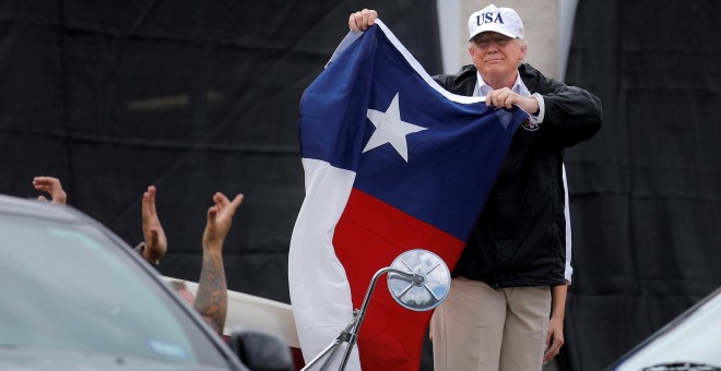 El presidente de EEUU Donald Trump sostiene una bandera de Texas tras su llegada al estado este martes, severamente afectado por el huracán Harvey, ya convertido en tormenta tropical. REUTERS