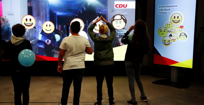 Varios niños observan una pantalla interactiva que muestra las propuestas de la CDU de Angela Merkel, en Berlín. REUTERS/Fabrizio Bensch