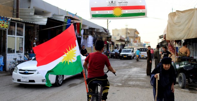 Un niño en bicicleta con la bandera del Kurdistán en una localidad de Irak. REUTERS/Thaier Al-Sudani