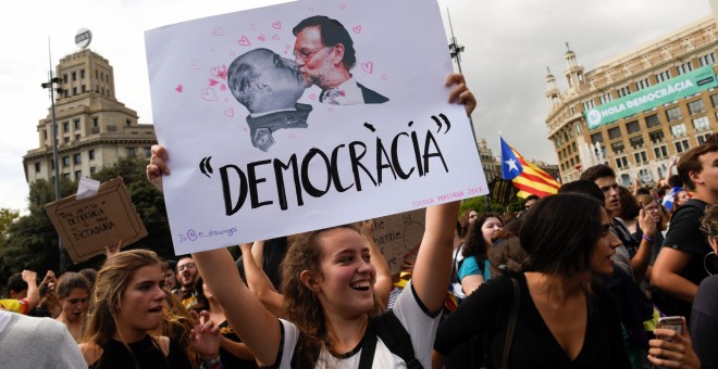 Una mujer sostiene un cartel que muestra al presidente de Gobierno, Mariano Rajoy, y al dictador Francisco Franco, sobre el mensaje 'Democracia', durante la manifestación en repulsa de las escenas de violencia policial que se vivieron el 1-O. REUTERS/Eloy