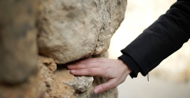 Una mano acaricia la textura de la piedra