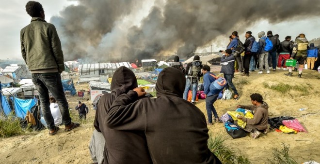 Imagen de octubre de 2016. Varios inmigrantes que vivían en la Jungla de Calais observan el desmantelamiento del campamento. - AFP