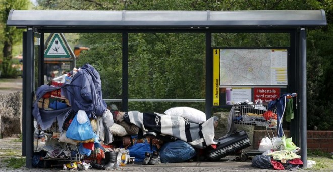 Una persona sin techo duerme en una parada de autobús./REUTERS