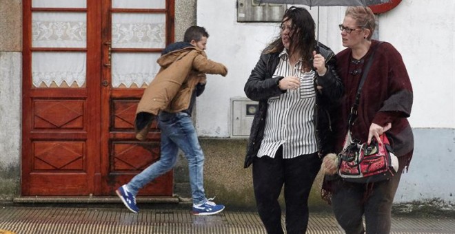 Dos mujeres se protegen de la lluvia y el viento mientras cruzan la calle.EFE/Eliseo Trigo