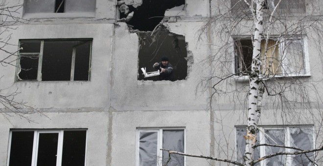 Un hombre lanza escombros desde un edificio en ruinas por los estragos de la guerra en Ucrania./REUTERS