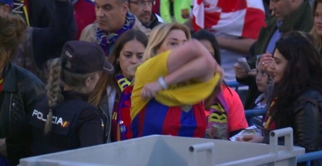 Una aficionada del FC Barcelona es treu una samarreta groga abans de la final de Copa del Rei, en presència d'una agent de la Policia Nacional. | CCMA.