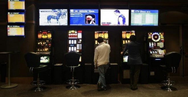 Varias personas juegan en máquinas tragaperras en un local de juegos en Madrid. REUTERS/Susana Vera