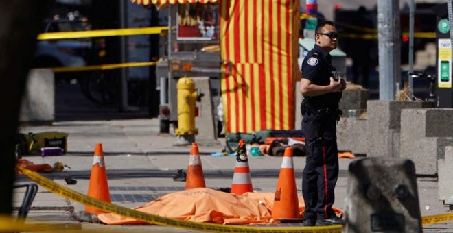 Un policía permanece de pie al lado de una de las víctimas del atropello. | (REUTERS)