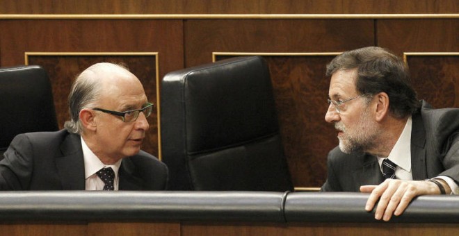 El presidente del Gobierno, Mariano Rajoy, conversa con el ministro de Hacienda, Cristóbal Montoro, en sus escaños de la bancada azul del Congreso de los Diputados. EFE
