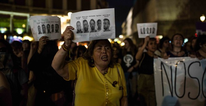 Una mujer muestra las caras de los cinco integrantes de 'la manada' durante la manifestación contra su sentencia condenatoria en Madrid.- JAIRO VARGAS