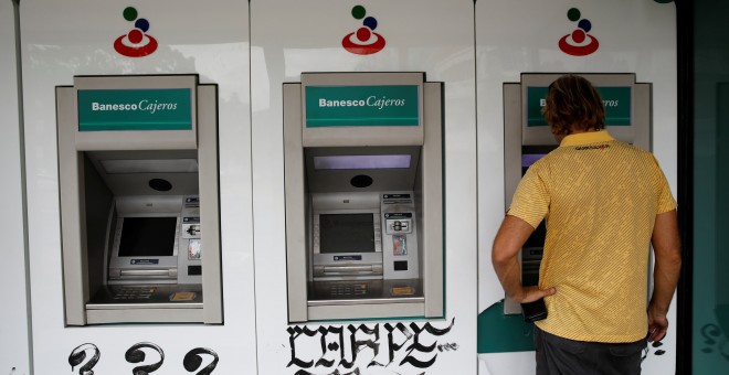 Un hombre utiliza un cajero automático en una sucursal del banco Banesco, en Caracas. REUTERS/Carlos Garcia Rawlins
