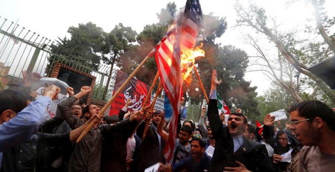 Un grupo de iraníes quema una bandera estadounidense mientras participan en una protesta contra Estados Unidos frente a la antigua embajada estadounidense en Teherán (Irán). / EFE