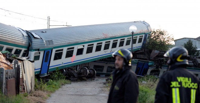 Dos bomberos junto al tren accidentado en Caluso, Italia. - REUTERS