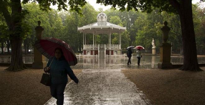 Paseantes se protegen de la lluvia en el parque de la Florida de Vitoria, País Vasco. / EFE