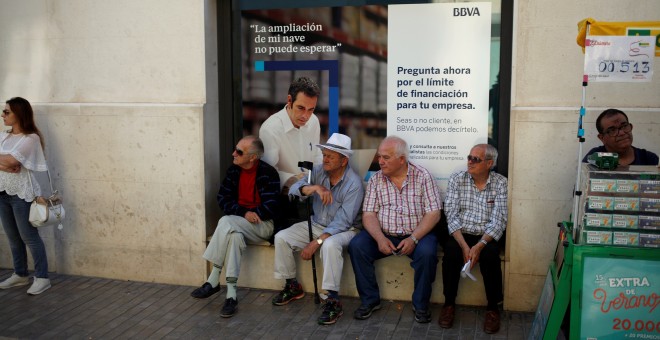 Varios pensionistas sentados en la ventada de una sucursal del BBVA en el cenro de Málaga.. REUTERS/Jon Nazca