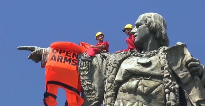 Dos activistes de Proactiva Open Arms col·loquen una armilla gegant a l'estàtua de Colon. CCMA