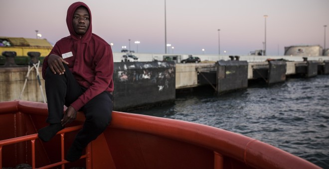 Abdoul Kalash, de 15 años y originario de Guinea Konacry, observa Algeciras desde el puerto, donde lleva durmiendo tres días seguidos tras ser rescatado en el Estrecho de Gibraltar cuando viajaba en una patera. JAIRO VARGAS