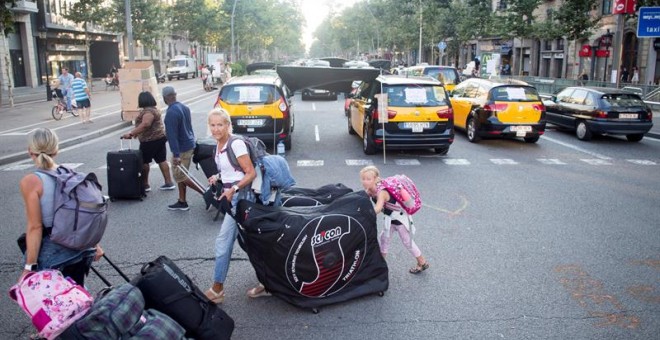 31/07/2018.- Unos turistas llevan sus maletas mientras los taxistas mantienen las concentraciones en el centro de la ciudad con motivo de la huelga iniciada el pasado 25 de julio, por el conflicto de las licencias VTC (alquiler de vehículos con conductor)