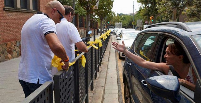 Una mujer increpa a miembros a dos personas que retiran lazos amarillos en la localidad de Alella. (ALEJANDRO GARCÍA | EFE)