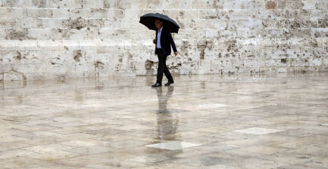 Un hombre en el casco antiguo de Valencia protegido con un paraguas - EFE / Kai Foersterling