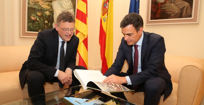 El presidente del Gobierno, Pedro Sánchez, hojea un libro en presencia del presidente de la Generalitat Valenciana, Ximo Puig.