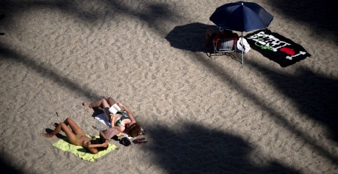 Dos mujeres toman el sol en la playa Burriana, en la localidad mañagueña de Nerja. AFP/Jorge Guerrero