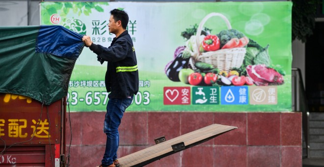 Un trabajador ajusta la lona de su camión junto a un supermercado en la localidad china de Chongqing. REUTERS/Stringer