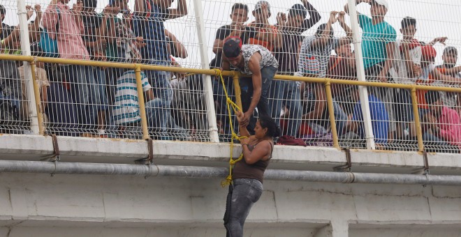 Una migrante trata de escalar el puente que cruza el río que une México con Honduras.REUTERS/Edgard Garrido