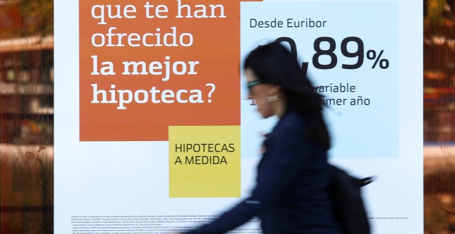 Una mujer pasa junto a una publicidad de hipotecas en una sucursal de Bankinter. REUTERS/Susana Vera