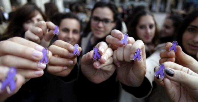 Un grupo de jóvenes muestran pines con lazos morados contra la violencia machista. EFE/Archivo