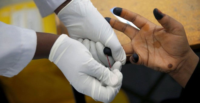 Un consejero sobre la adherencia al VIH extrae la sangre de una mujer para una prueba de VIH en el centro de tratamiento de la OIM en Eastleigh, Nairobi