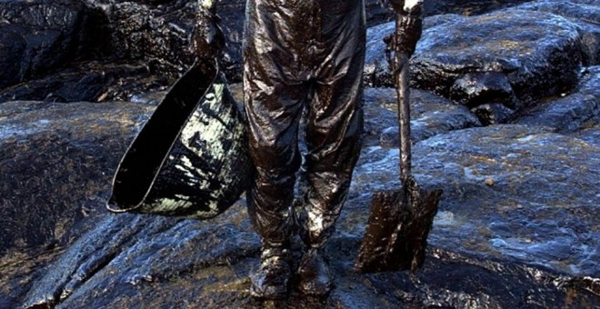 Un voluntario recoge el petróleo vertido por el Prestige. / ALBERTO ESTÉVEZ (EFE)