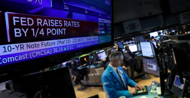 Un monitor de televisión en el patio de negociación de la bolsa de Nueva York (NYSE) en Wall Street, con la información de la subida de los tipos de interés decidida por la Reserva Federal. REUTERS/Brendan McDermid