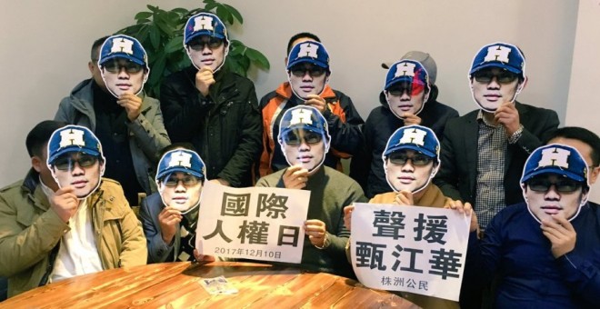 Varias personas posan con una máscara con la cara del activista chino Zhen Jianghua como muestra de apoyo tras su detención en septiembre de 2017.-CHINA CHANGE