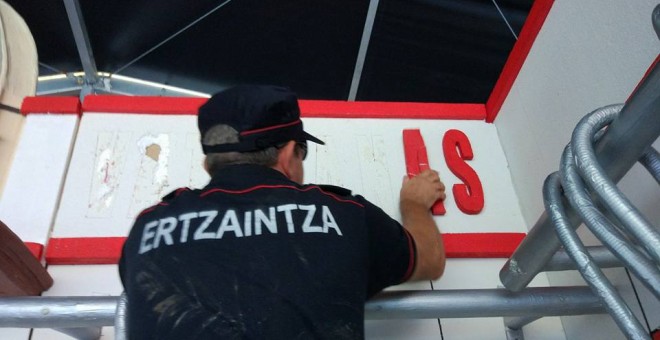 Un ertzaina retira la decoración de la comparsa anarquista Hontzak