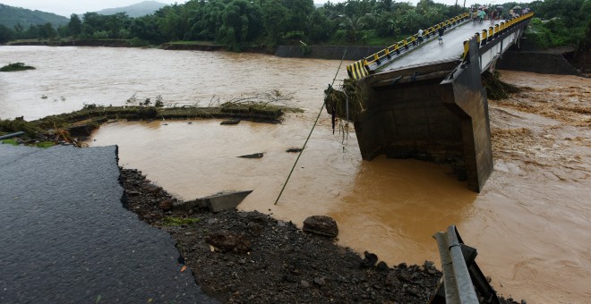 Locals look into a damaged bridge after floods hit Manuju in Gowa, South Sulawesi, Indonesia, January 23, 2019 in this photo taken by Antara Foto. Picture taken January 23, 2019. Antara Foto/Yusran Uccang/ via REUTERS ATTENTION EDITORS - THIS IMAGE WAS PR