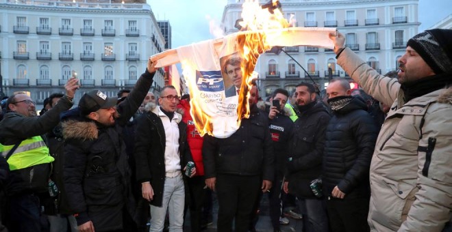 Los taxistas queman un cartel del PP con la cara del presidente de la Comunidad de Madrid en  segundo día consecutivo en la madrileña Puerta del Sol. (KIKO HUESCA | EFE)