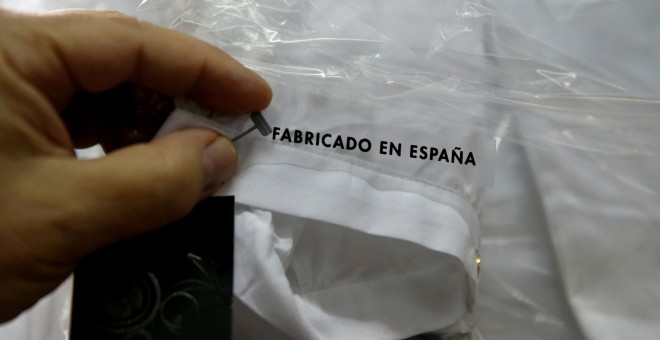 Un trabajador sostiene una etiqueta que pone 'Hecho en España' en una camisa en una fábrica textil en Madrid. REUTERS/Andrea Comas