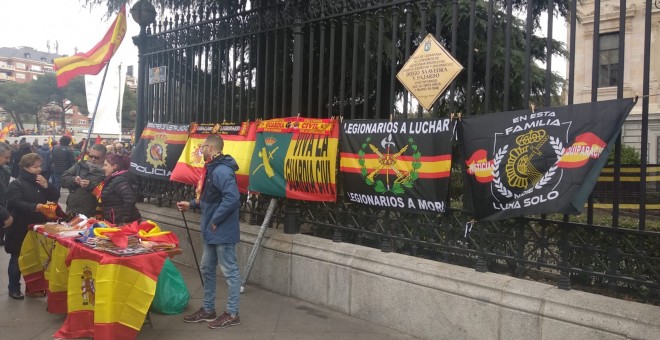 Un hombre vende banderas de España y símbolos de la Policía Nacional y Guardia Civil en los aledaños de Colón