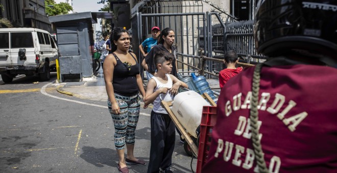 Una familia se topa con una calle cortada por la marcha cuando va a recoger agua en Caracas.