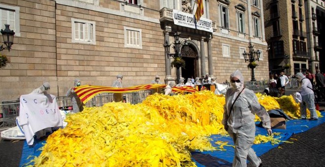 Integrantes del grupo antiindependentista 'Els Segadors del Maresme', vestidos con monos blancos, con la cara tapada con mascarillas y con gafas de sol, han volcado este sábado en la plaza de Sant Jaume, frente al Palau de la Generalitat, una decena de s