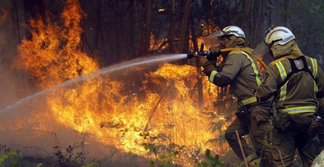 Los bomberos apagan uno de los numerosos focos del incendio en la localidad coruñesa de Rianxo. (LAVANDEIRA JR. | EFE)