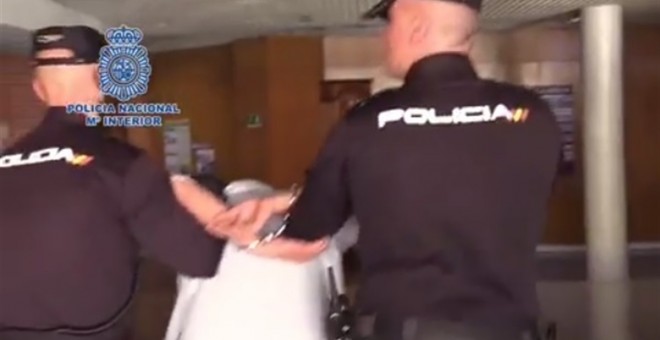 Dos agentes trasladan al detenido, acusado de matar a un vecino en el barrio madrileño de Vallecas.