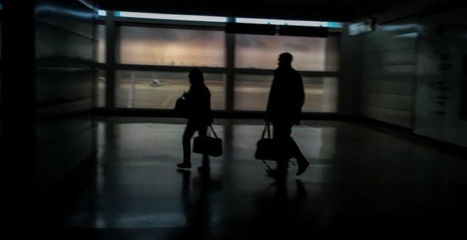 Dos personas caminan este miércoles por un pasillo del aeropuerto internacional 'Simón Bolívar' totalmente a oscura. /MIGUEL GUTIÉRREZ (EFE)