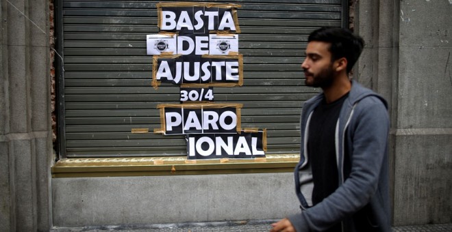 Un hombre para junto a un cartel que llama a la huelga, este martes en Buenos Aires. REUTERS/Agustín Marcarian