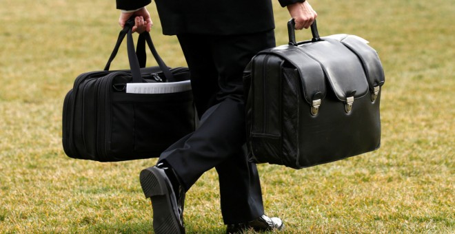 Un asistente militar estadounidense, con los maletines que contienen los códigos de lanzamiento para armas nucleares, que lleva el presidente Donald Trump. REUTERS
