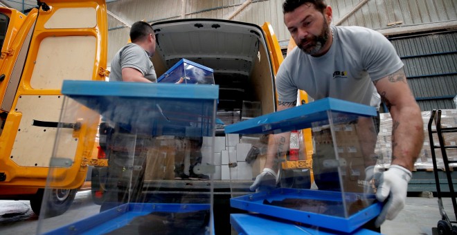 Los trabajadores cargan las urnas cuando las llevan de un almacén para enviarlas a los colegios electorales, antes de las elecciones al Parlamento Europeo en Barcelona. Reuters