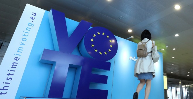 Una mujer pasa frente a un tablero publicitario para las elecciones de la UE en la estación de tren Schuman cerca del Parlamento Europeo en Bruselas. Reuters